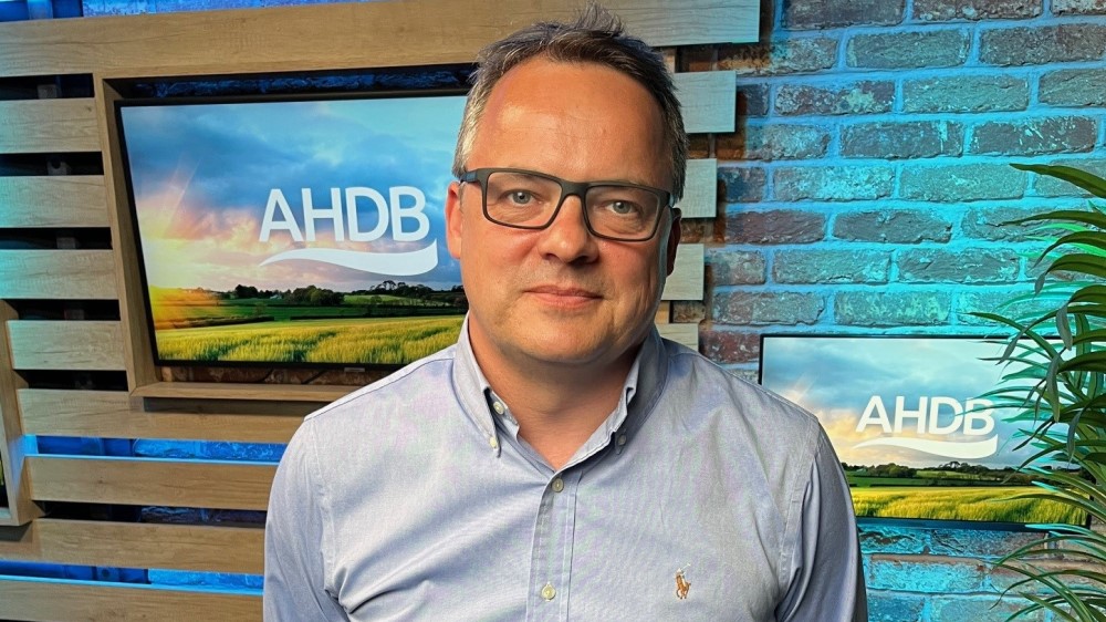 Graham Wilkinson standing in front of screens showing the AHDB logo